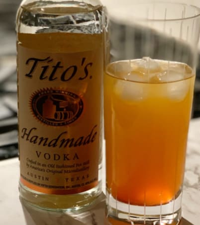 Tito's Vodka bottle beside mixed drink